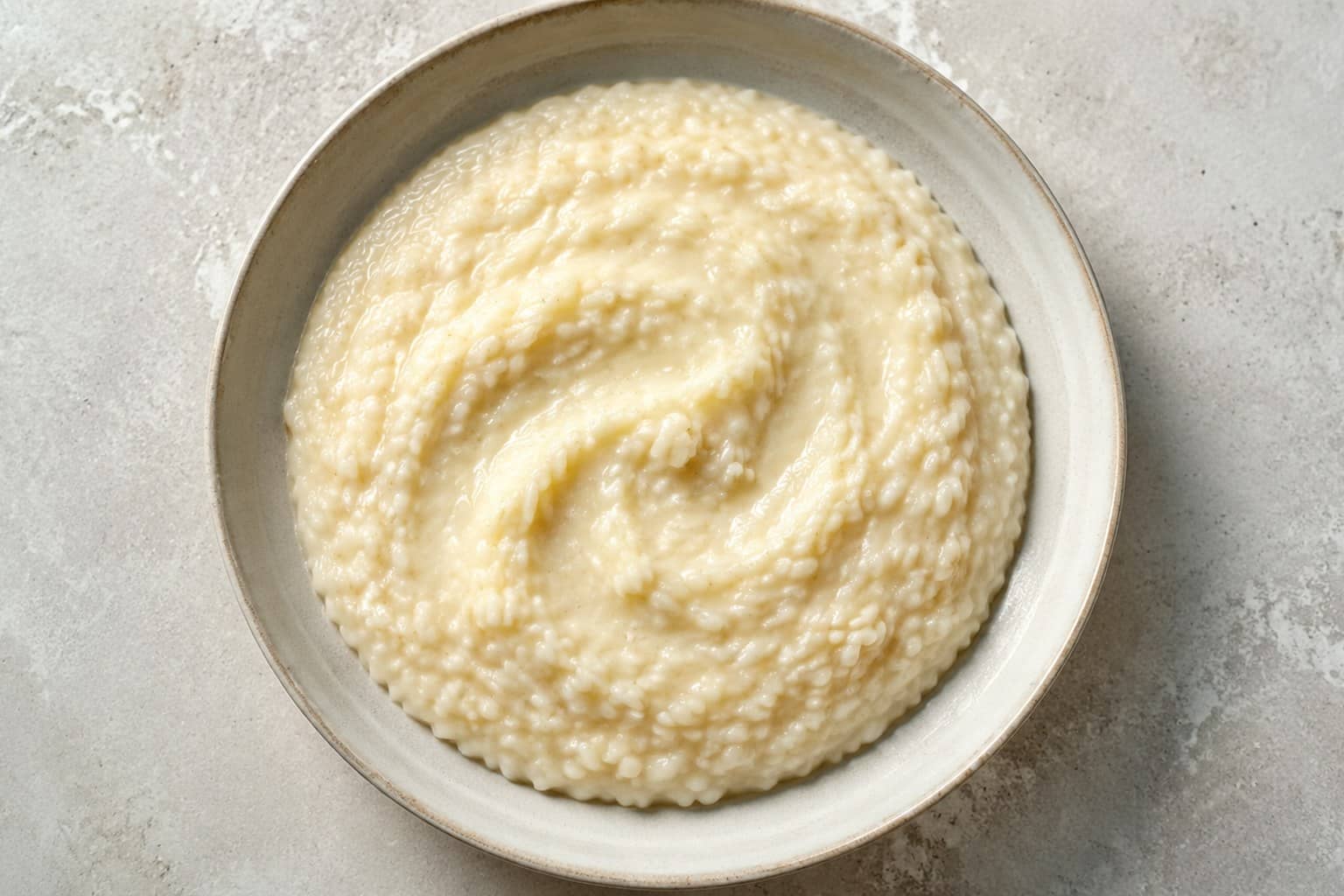 Cremet parmesanrisotto med smeltet smør og friskrevet parmesan i hvid skål