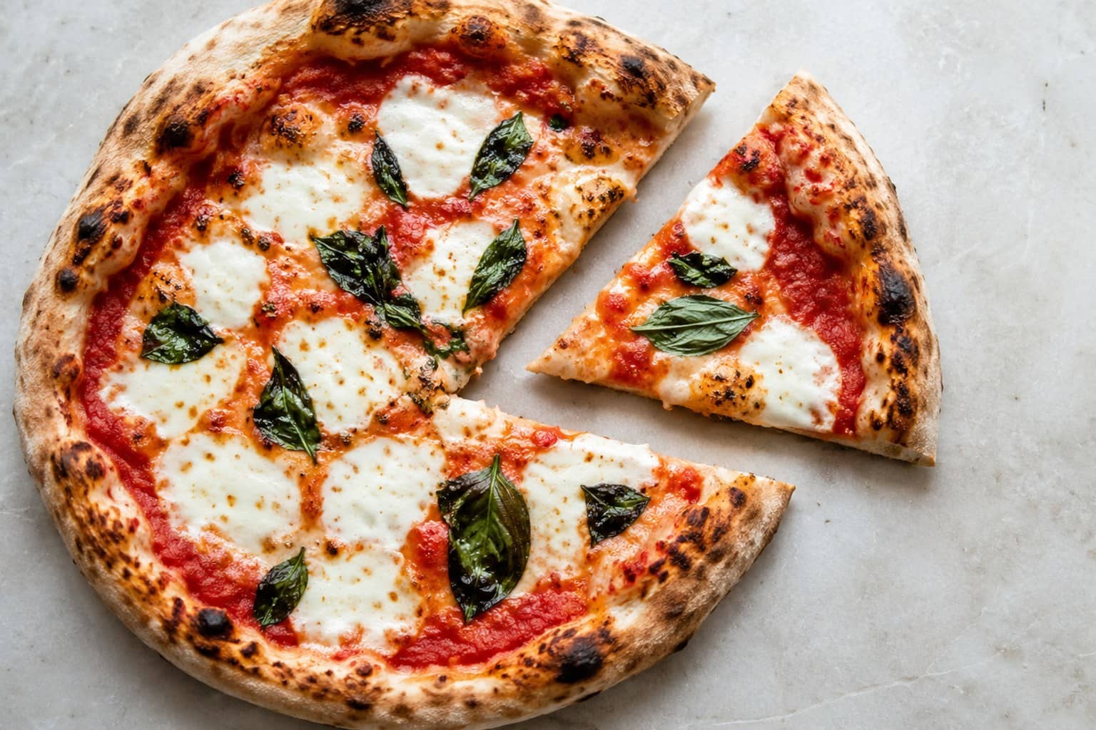 Nybagt pizza margherita med boblende mozzarella, tomatsauce, friske basilikumblade og gylden, luftig kant