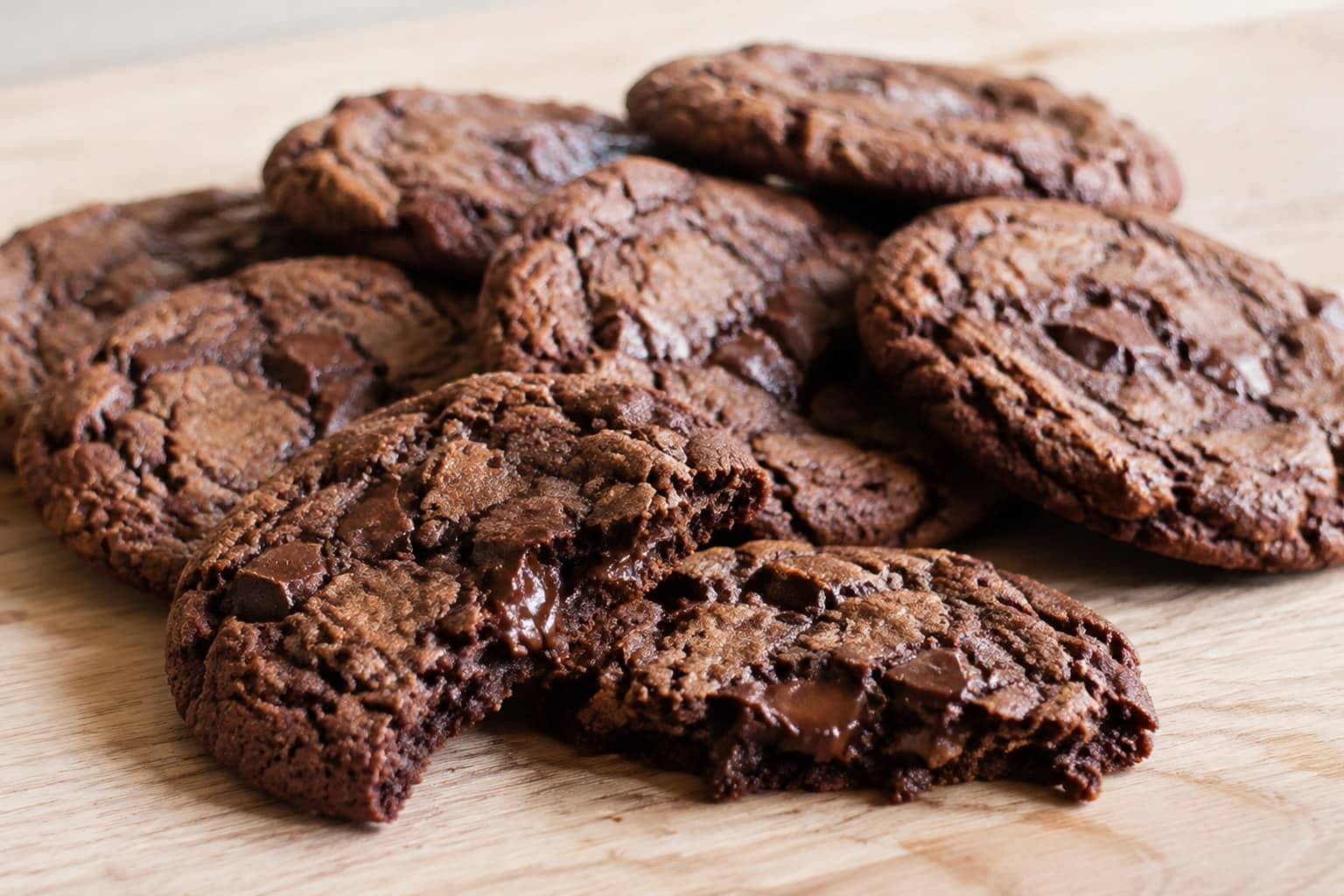 Gyldne cookies med smeltede stykker mørk chokolade, sprøde kanter og blød midte på bagepapir