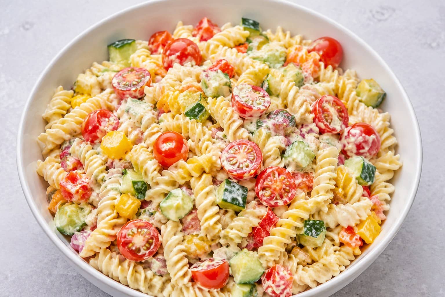 Stor skål med colorful pastasalat med mozzarella, cherrytomater og basilikum