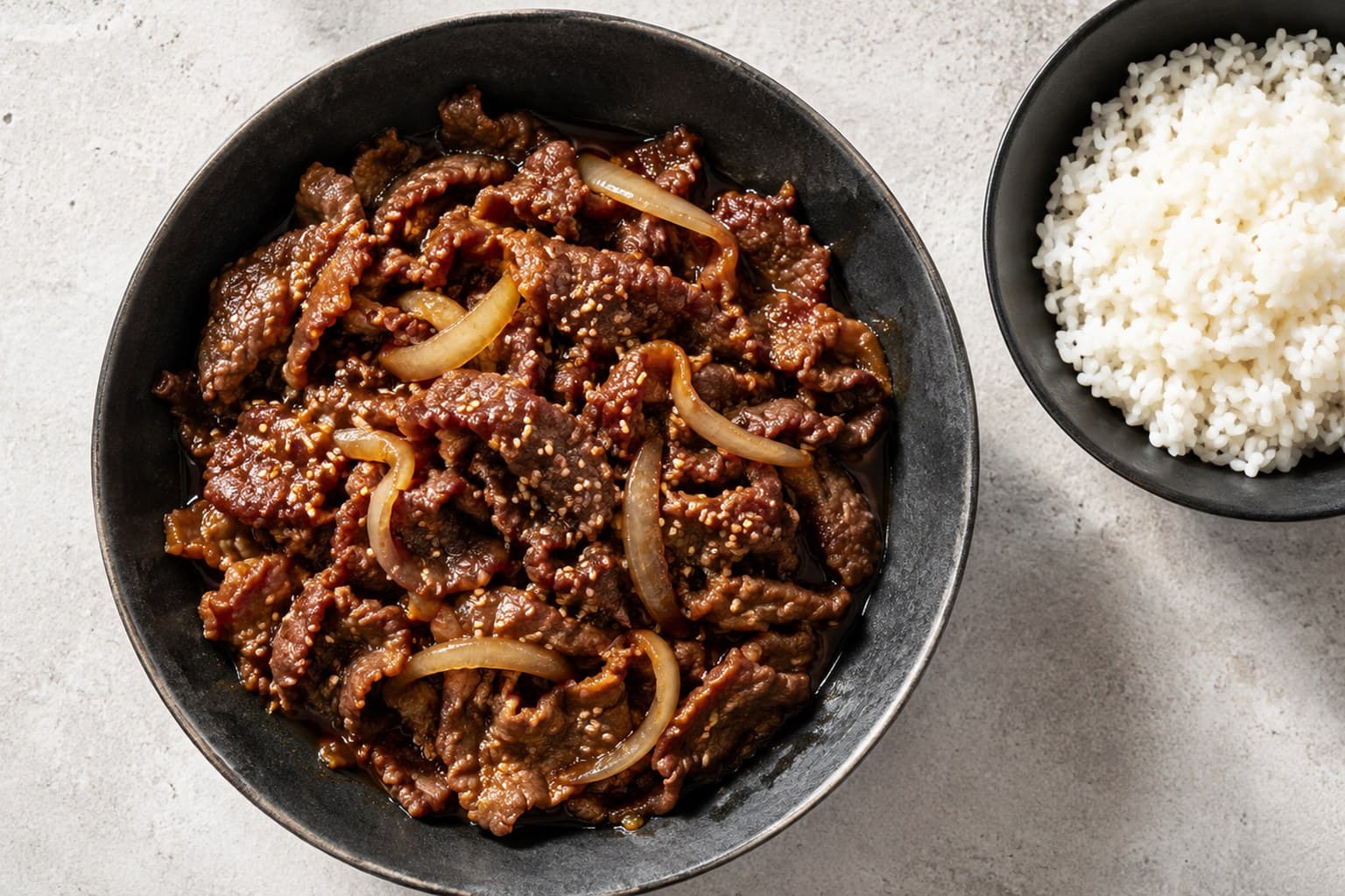 Koreansk bulgogi med tynde oksekødsstrimler i sort skål med ris og sesamfrø