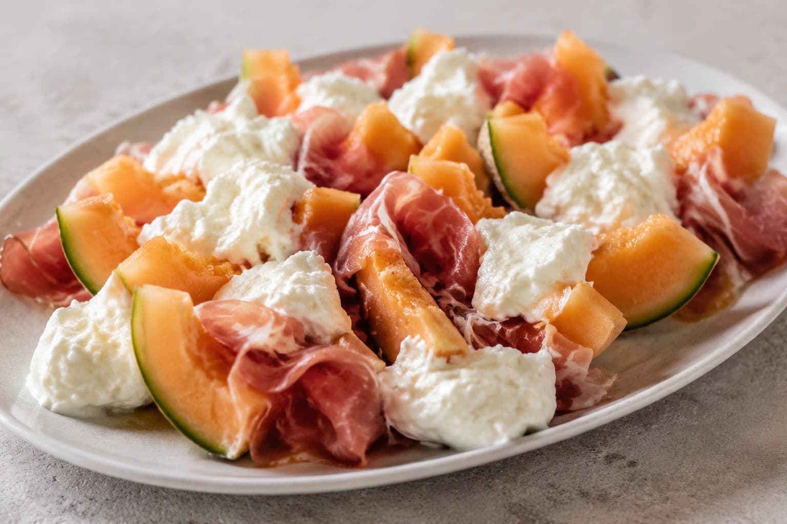 Melon med prosciutto og burrata, klassisk sommerforret, anrettet og klar til servering
