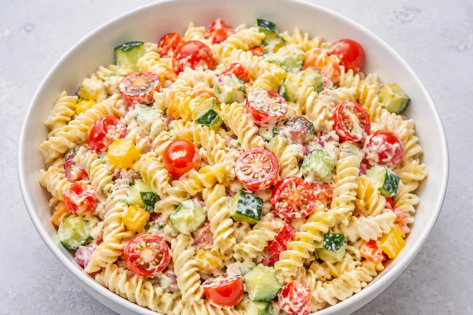 Stor skål med colorful pastasalat med mozzarella, cherrytomater og basilikum